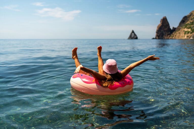 Summer vacation woman in hat floats on an inflatable donut mattress. Happy woman relaxing and enjoying family summer travel holidays travel on the sea
