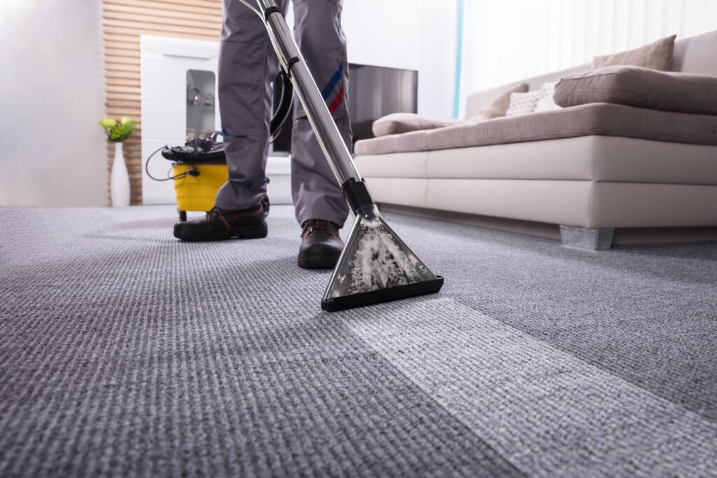 Person using a carpet vacuum to clean a dark colored carpet