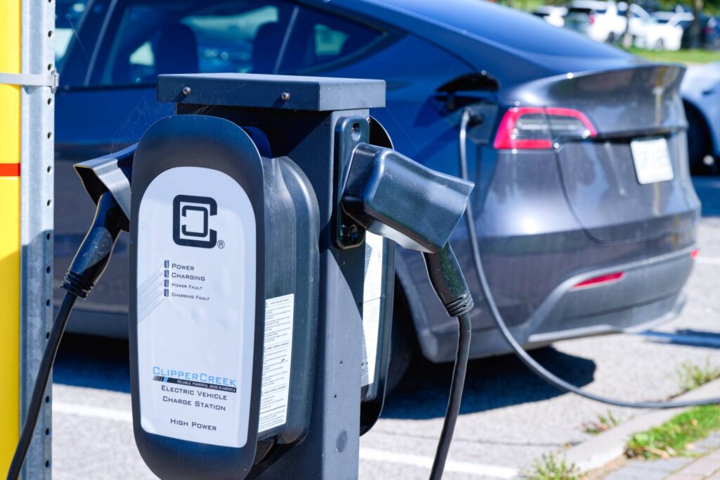 Public level 2 EV charger powering an electric car at a charging station