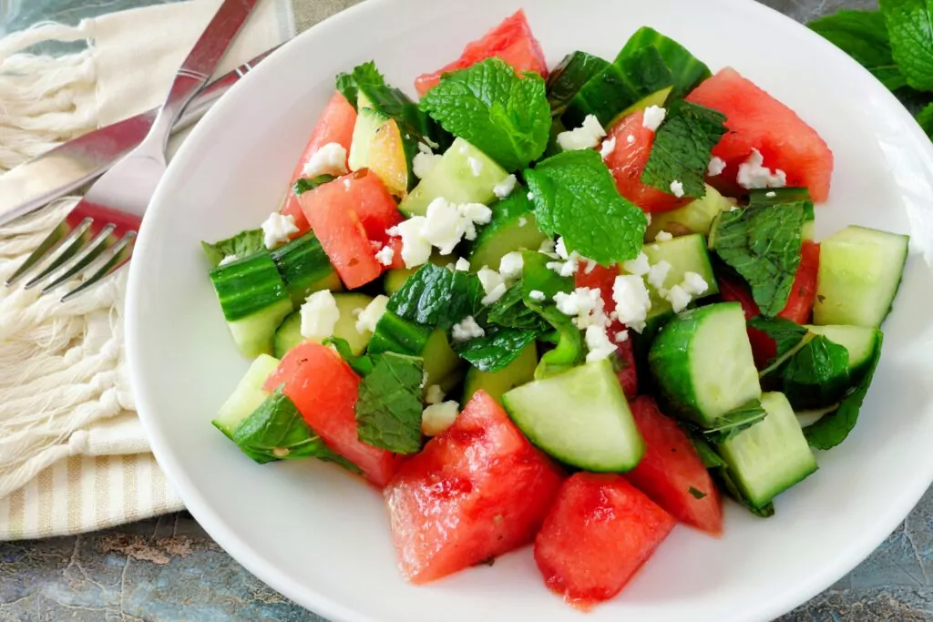 Summer salad with watermelon, mint, cucumber and feta cheese close up in a white plate